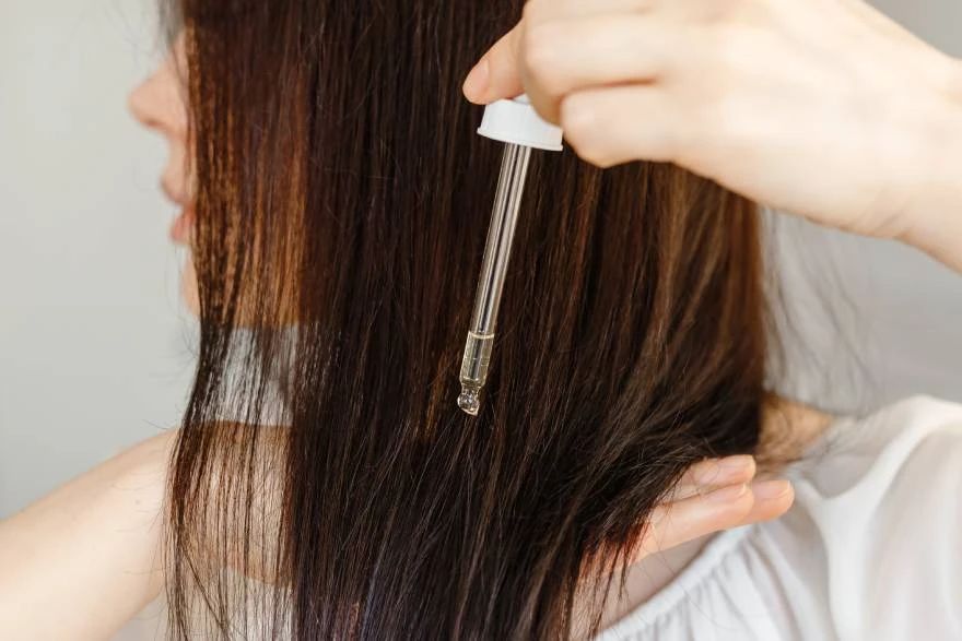 Žena koristi serum na svojoj kosi