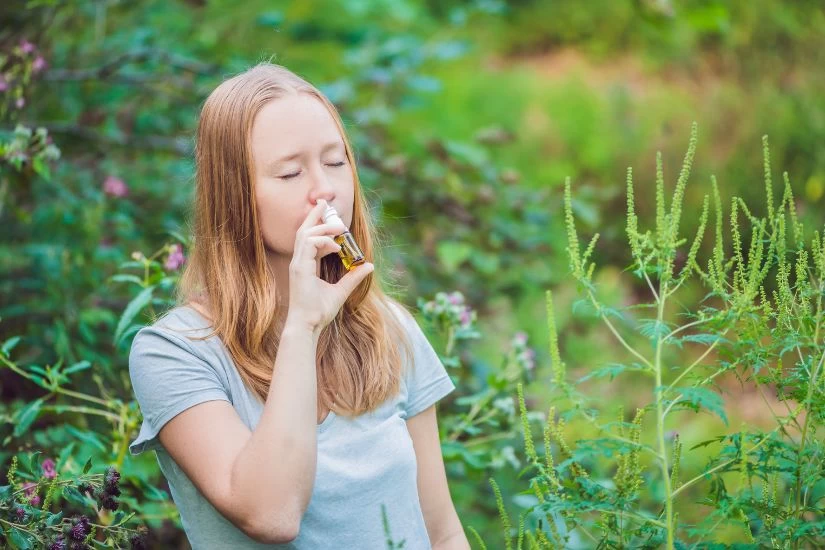 Devojka sa alergijom na ambroziju stavlja sebi sprej u nos.