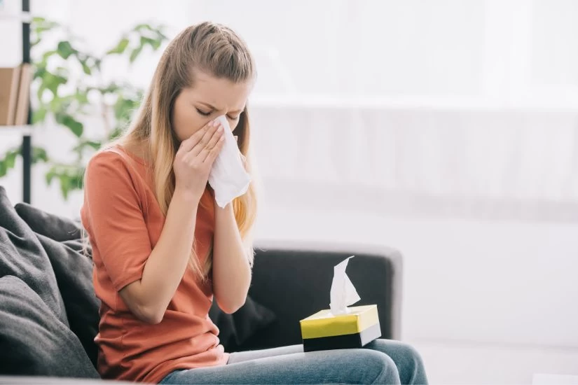 Devojka sa alergijom na ambroziju kija u maramicu.