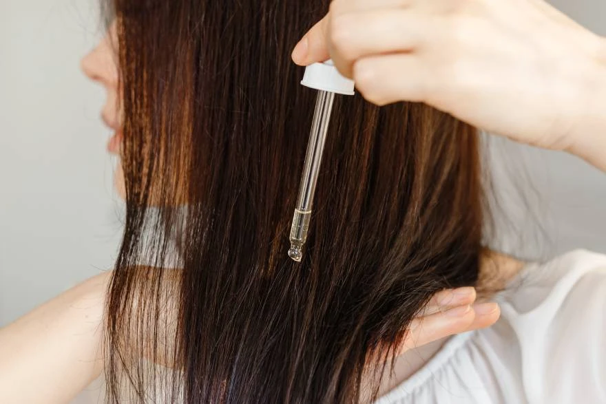 Žena koristi serum na svojoj kosi