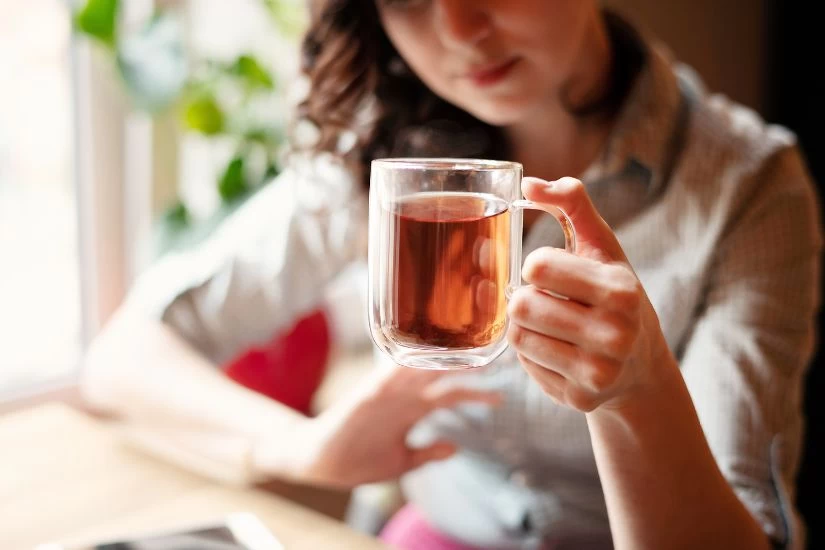 Žena pije čaj za urinarnu infekciju.