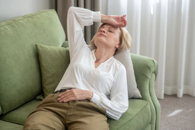 Žena sa valunzima u menopauzi leži na krevetu.